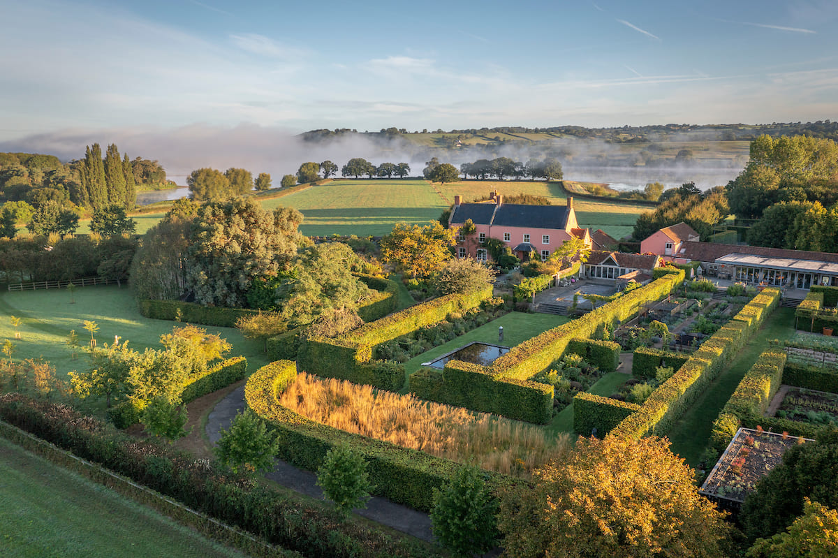 A well-developed garden enclosed with hedgerows. The countryside is visible in the background.